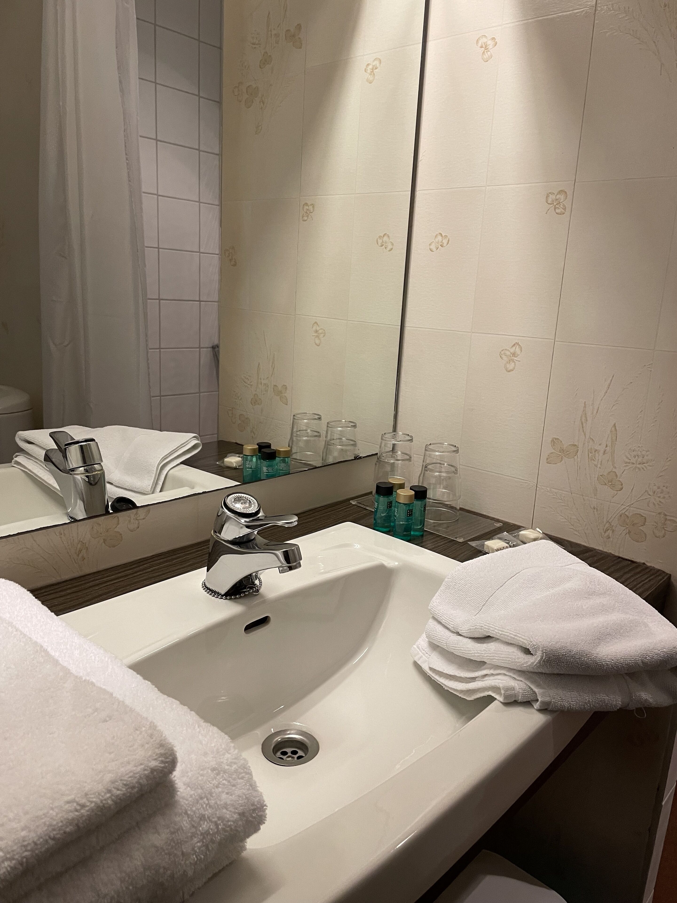 A bathroom with a white sink, a mirror, and a towel rack.