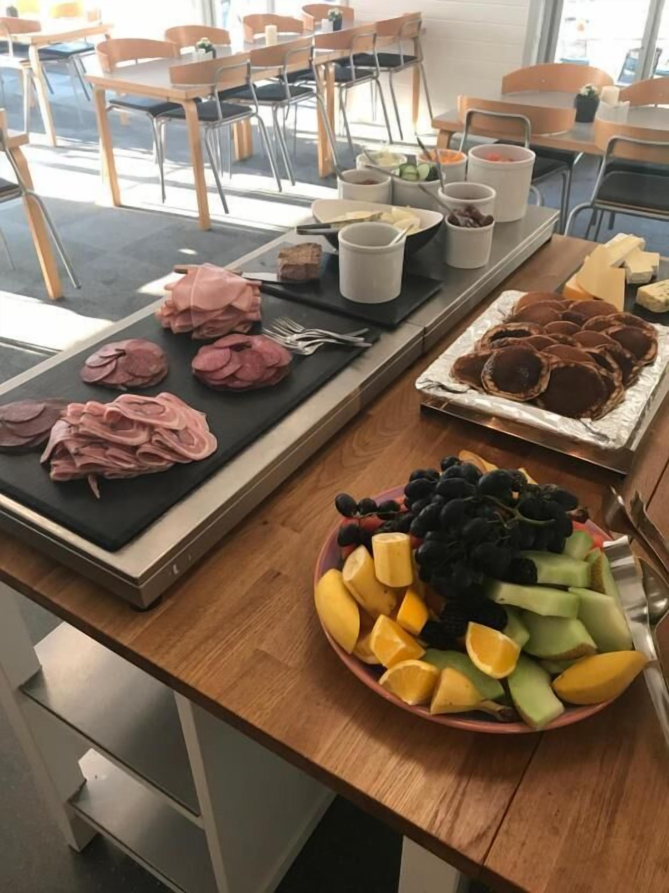 Un bufé de desayuno con diversas opciones de alimentos, incluyendo carnes, frutas y quesos.