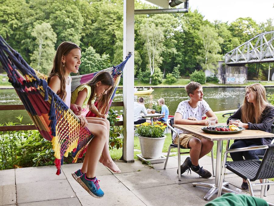 A patio area with a table set for dining, a hammock, and a view of a river and bridge.