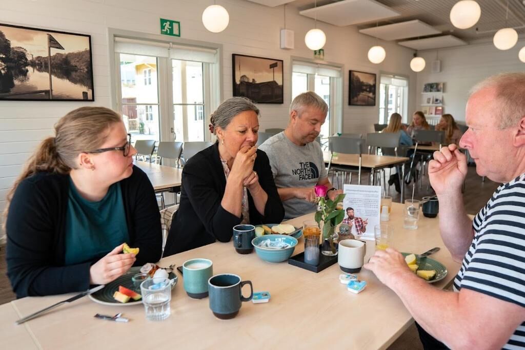A group of people dining in a restaurant with tables, chairs, and various food and drink items.
