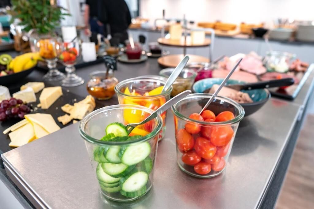 En buffet med forskellige spiser, herunder skivede agurker, cocktailtomater og ost.
