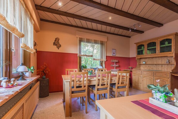 Comedor con mobiliario de madera, una pared de acento roja y una ventana con cortinas.