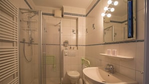 Une salle de bain avec une douche à parois de verre, des toilettes et un lavabo.