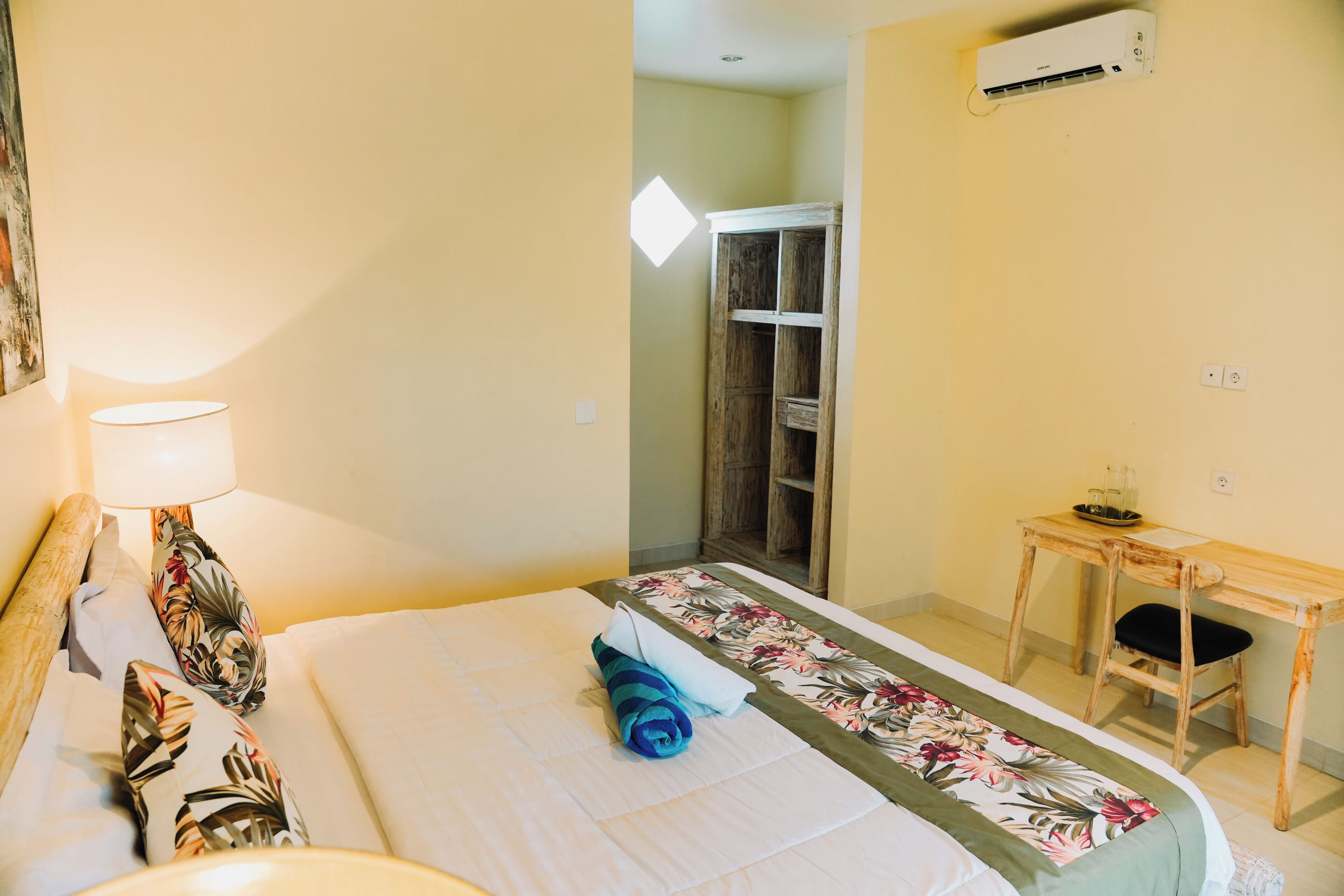Una habitación de hotel con cama, escritorio, lámpara y armario.