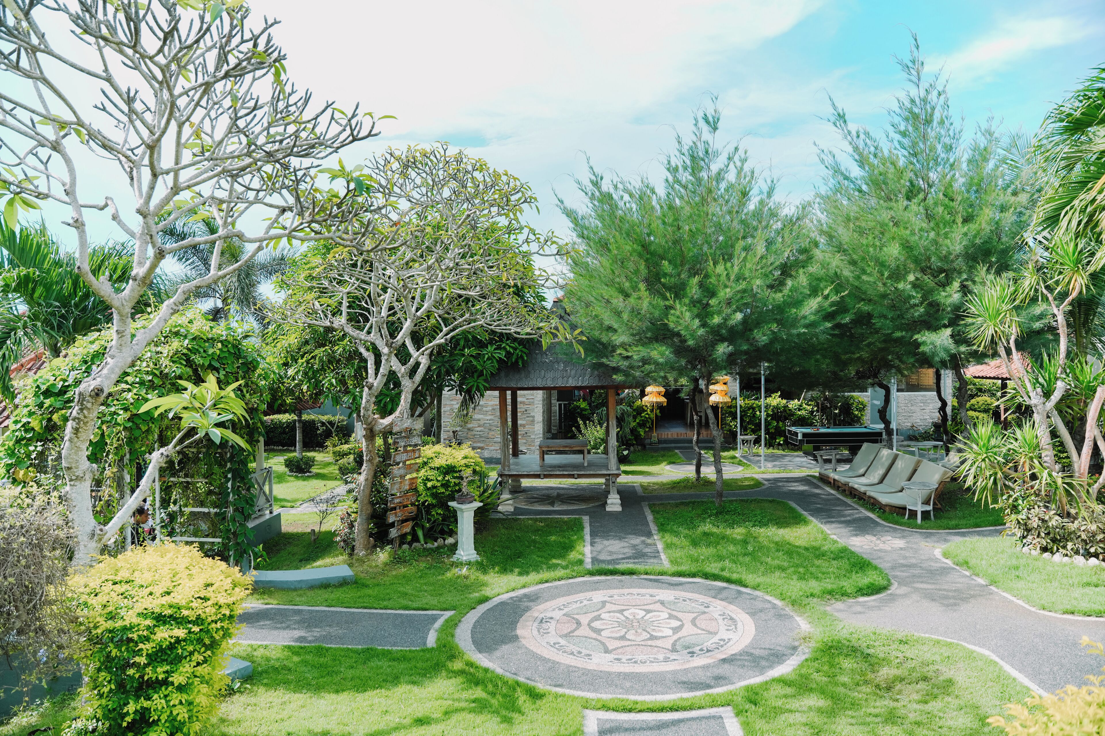 A garden with a gazebo, seating area, and a circular patterned walkway.