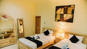 Une chambre d’hôtel avec deux lits en bois, chacun agrémenté de draps blancs et de touches noires. On y trouve une commode en bois avec un miroir, une œuvre d’art accrochée au mur et une lampe de chevet.