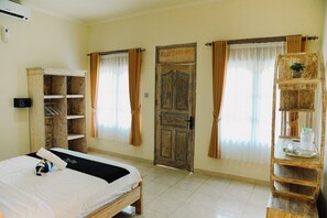 Une chambre à coucher avec un lit, une armoire en bois, une porte et une étagère sur laquelle se trouve une plante.