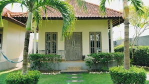 Une maison avec un toit en tuiles, une porte d’entrée et un petit porche avec des marches menant à la porte.