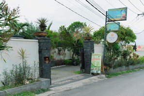 Une entrée fermée par un portail, avec une enseigne indiquant « Taman Ashling Homestay » et « Aesthetic Beauty Spa & Salon ».