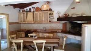 Una cucina rustica con mobili in legno, un tavolo da pranzo con sedie, un lampadario e un camino in mattoni.