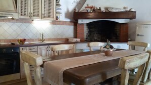 Una cucina con camino in mattoni, pensili in legno e un tavolo da pranzo con sedie.