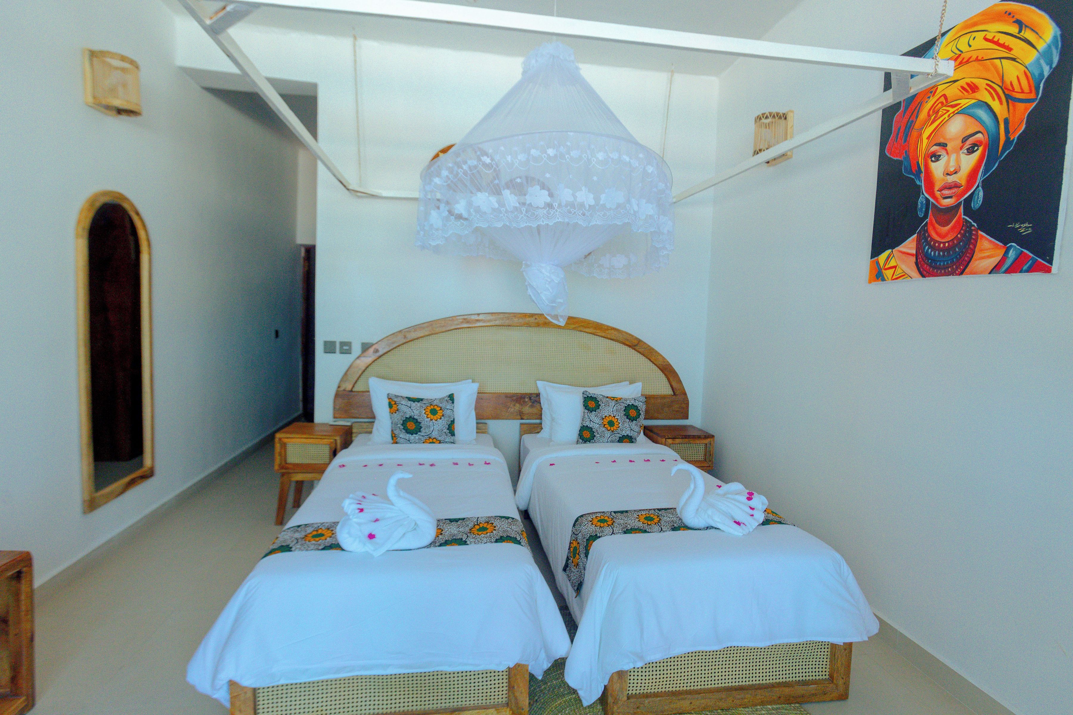 A room with two beds, a wooden headboard, a decorative hanging, and a painting on the wall.