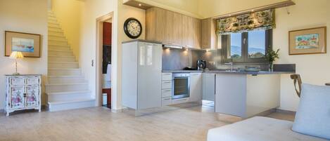 A modern kitchen with a built-in oven, a dining area with a sofa, and a staircase leading to another level.