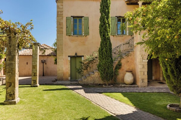 A courtyard with a stone building, a staircase, and a large vase.
