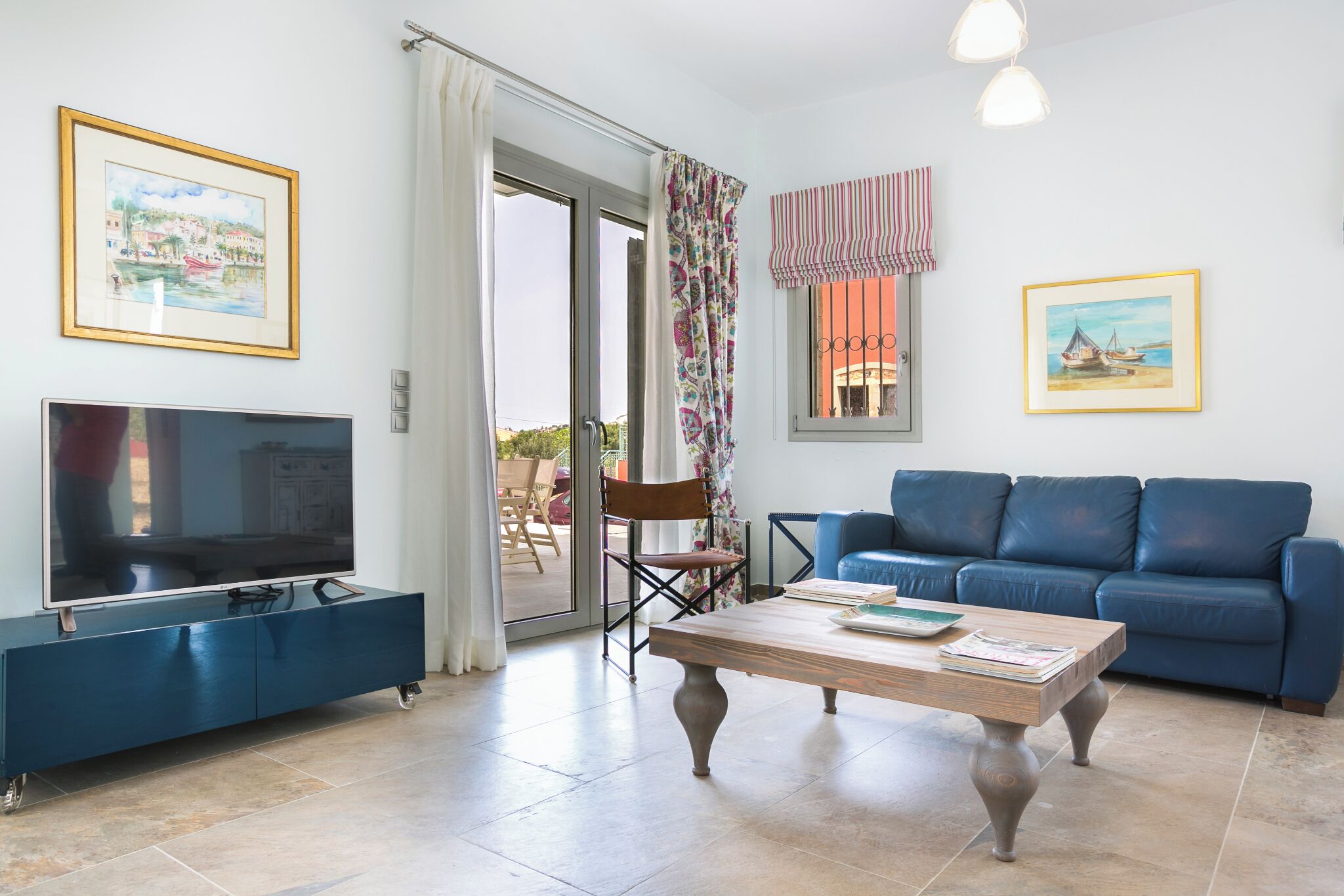 Ein Wohnzimmer mit Fernseher, Sofa, Couchtisch und zwei gerahmten Bildern.