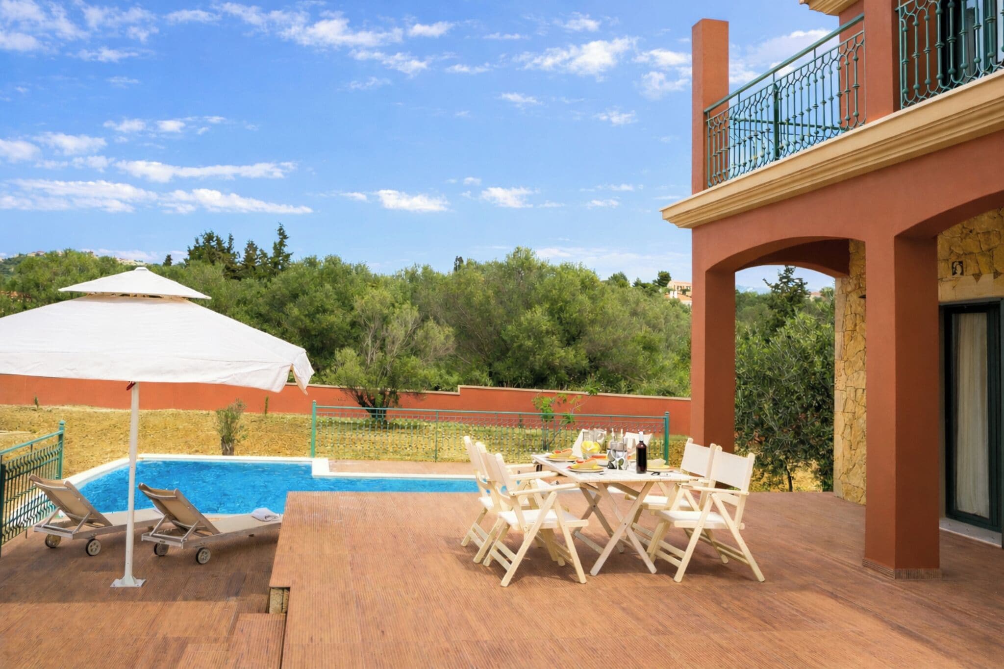 A poolside area with lounge chairs, a table, and a covered umbrella.