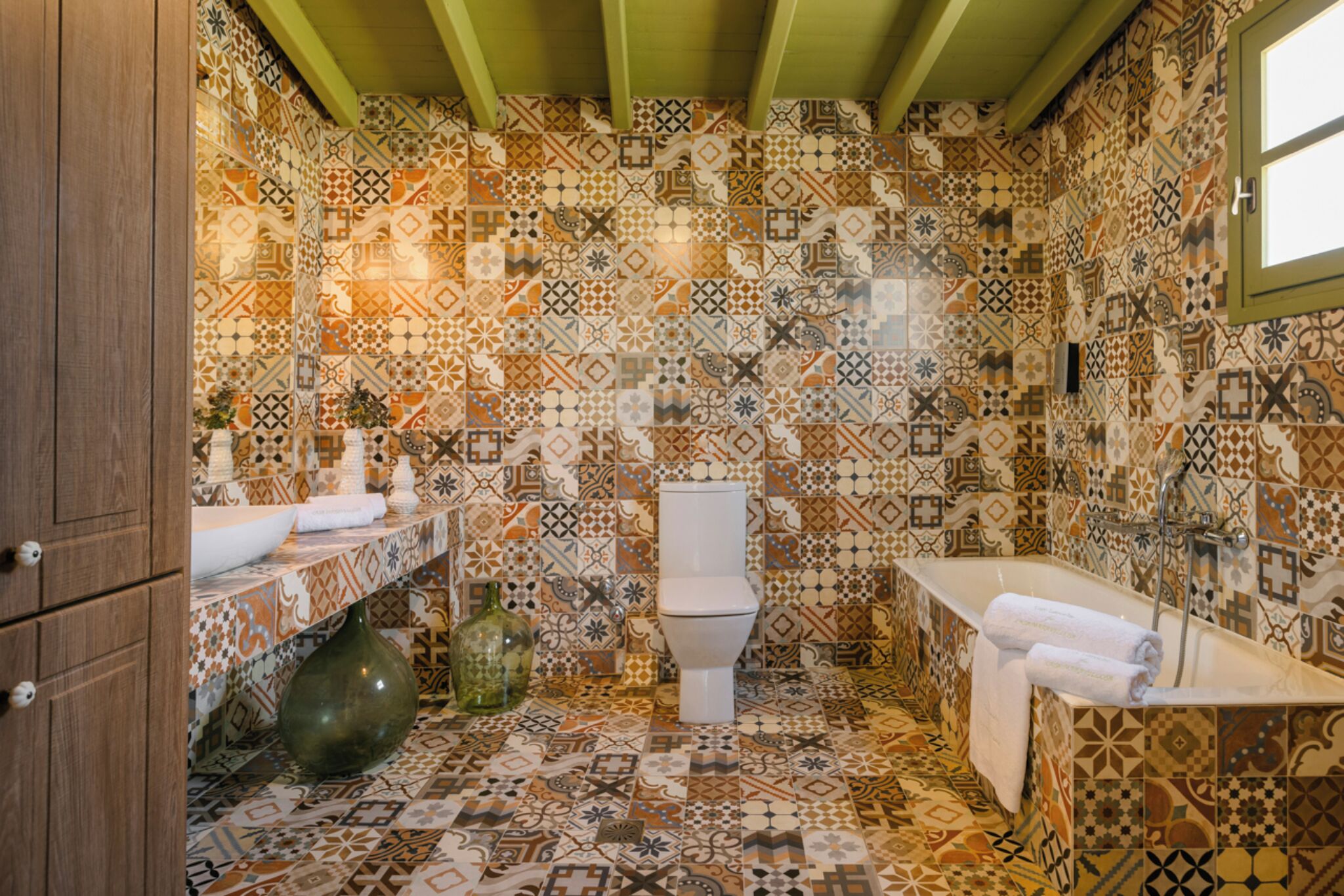Une salle de bain avec un sol carrelé à motifs, des toilettes, un lavabo et une baignoire.