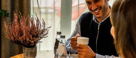 A round table with a potted plant, a menu, and a cup.