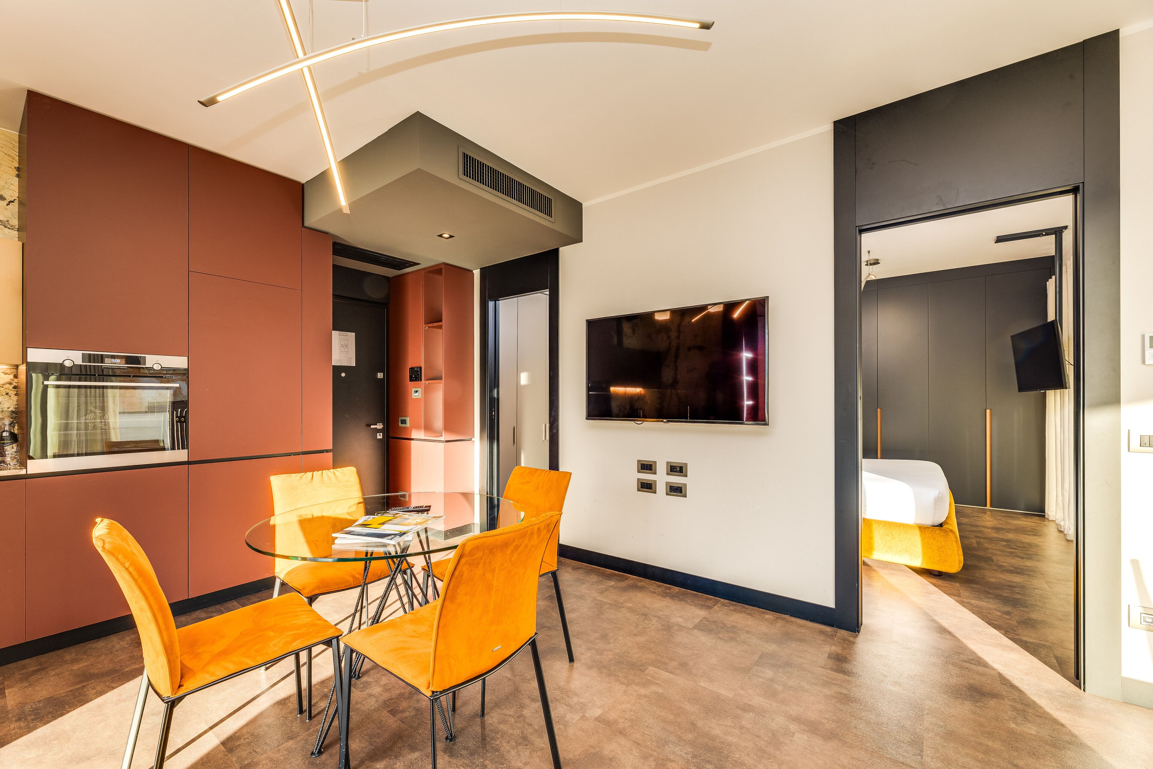 A modern kitchen with a dining area, a flat-screen TV, and a bed with a unique design.