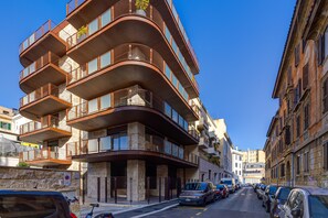 A multi-story building with balconies and a parking area in front. - Gasometer Urban Suites (Rome)