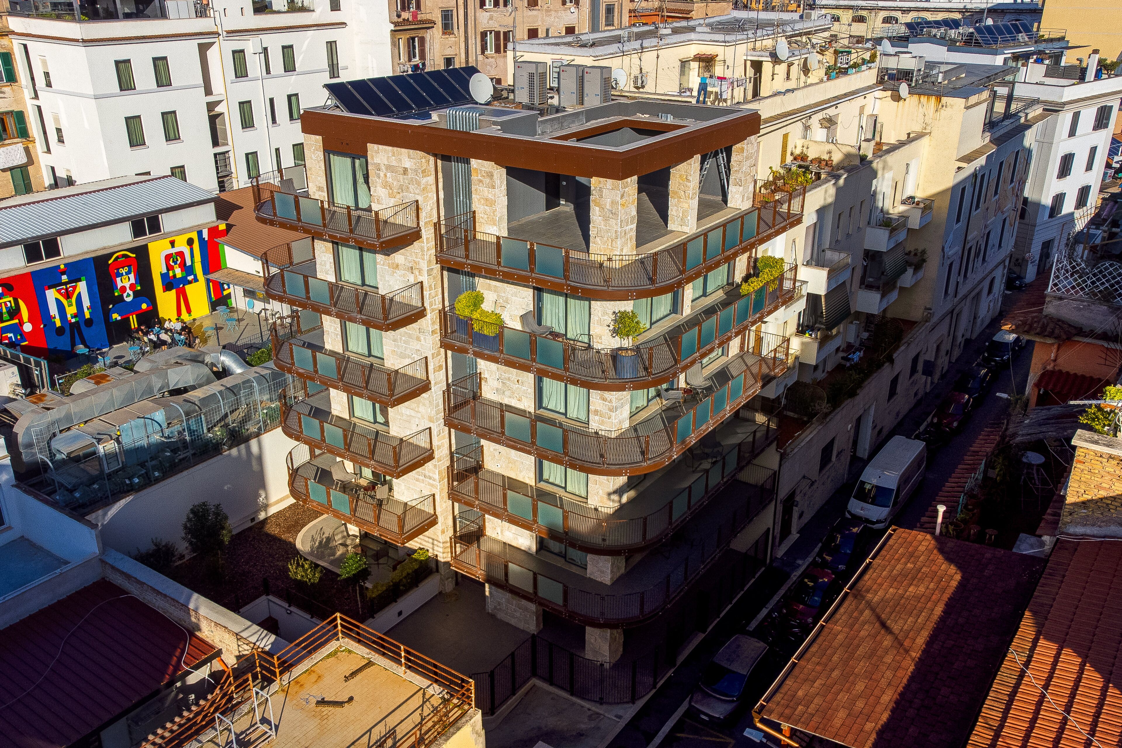 A multi-story building with balconies, solar panels, and a rooftop terrace.