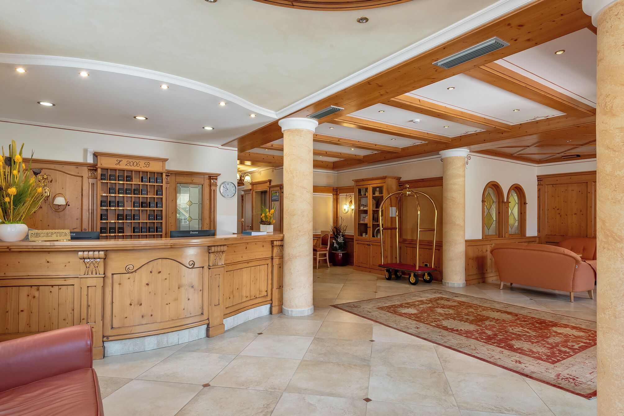 A spacious lobby with a reception desk, wooden cabinets, a clock, and a large column.
