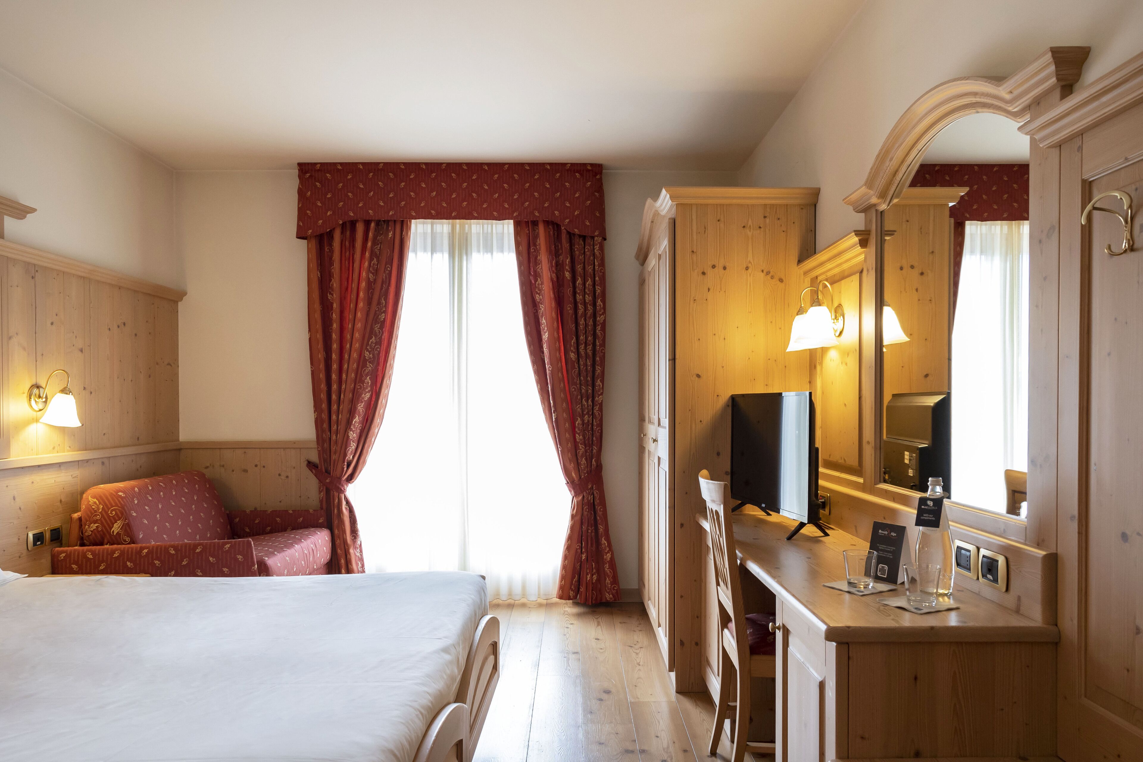 Une chambre d’hôtel avec un lit, un bureau doté d’un miroir et un téléviseur.