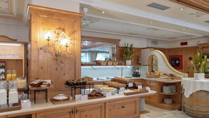 A breakfast buffet with various pastries and breads, wooden cabinetry, and a decorative wall-mounted light fixture. - Beverly Alps Hotel & Spa (Pinzolo)