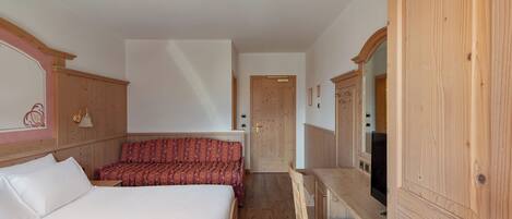 Une chambre à coucher avec un lit, un bureau et une chaise. Il y a une porte et un miroir sur le mur.
