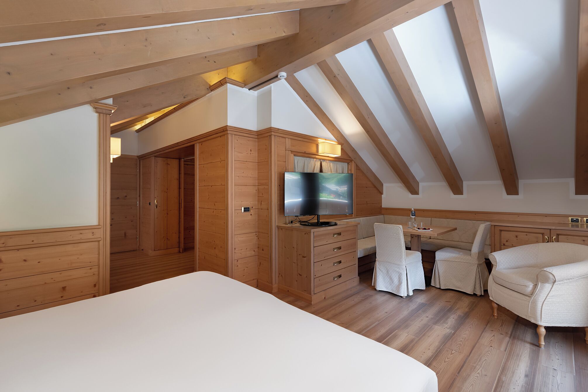Un dormitorio acogedor en el ático, con una cama grande, un armario de madera y un televisor.