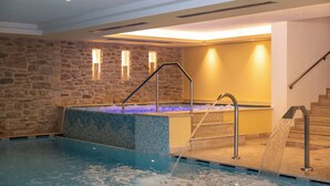 A swimming pool with a stone wall and a small waterfall feature. - Beverly Alps Hotel & Spa (Pinzolo)