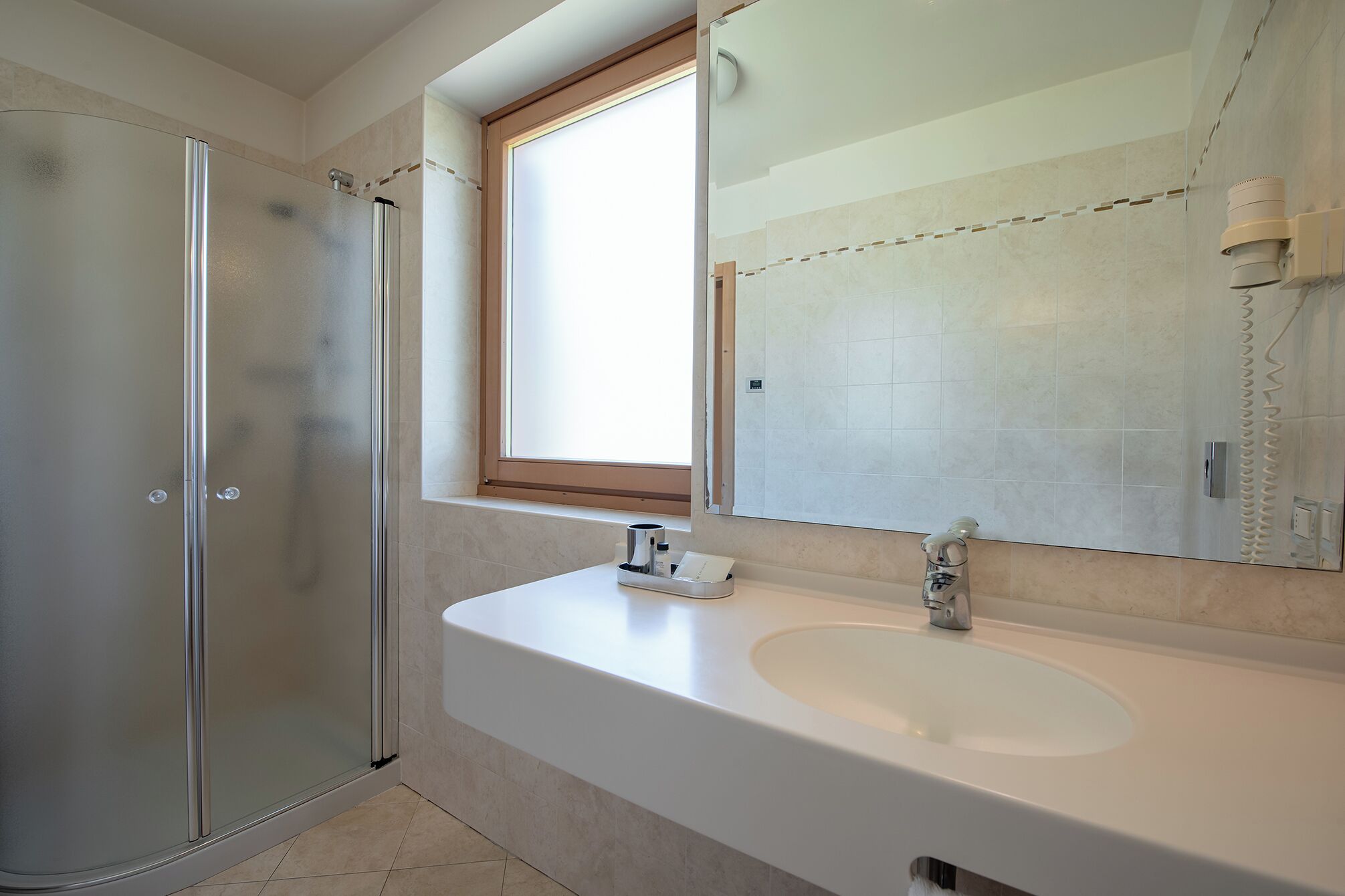 A modern bathroom with a glass shower enclosure, a large mirror, and a white sink.