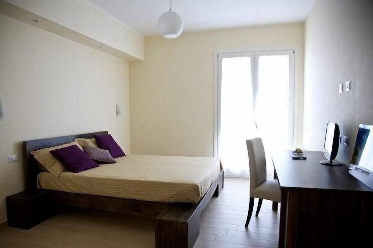 A bedroom with a bed, a desk, and a chair.