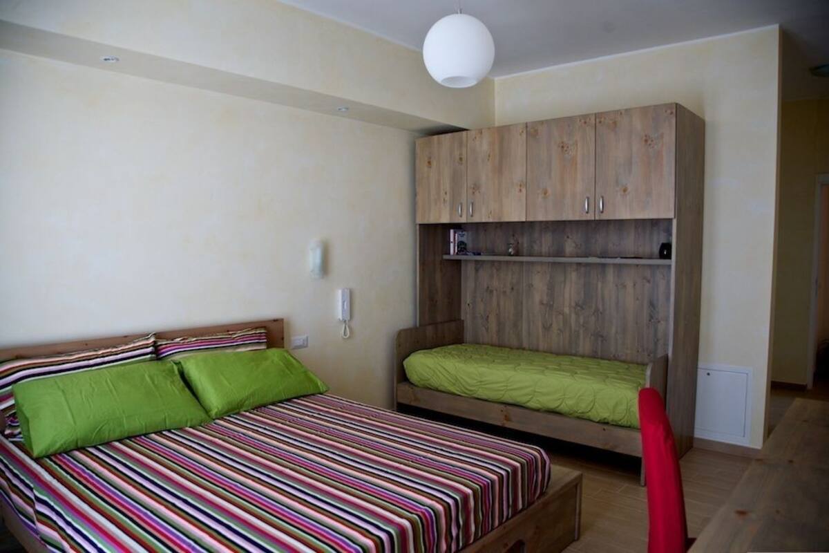 A bedroom with two beds, a wooden wardrobe, and a red chair.