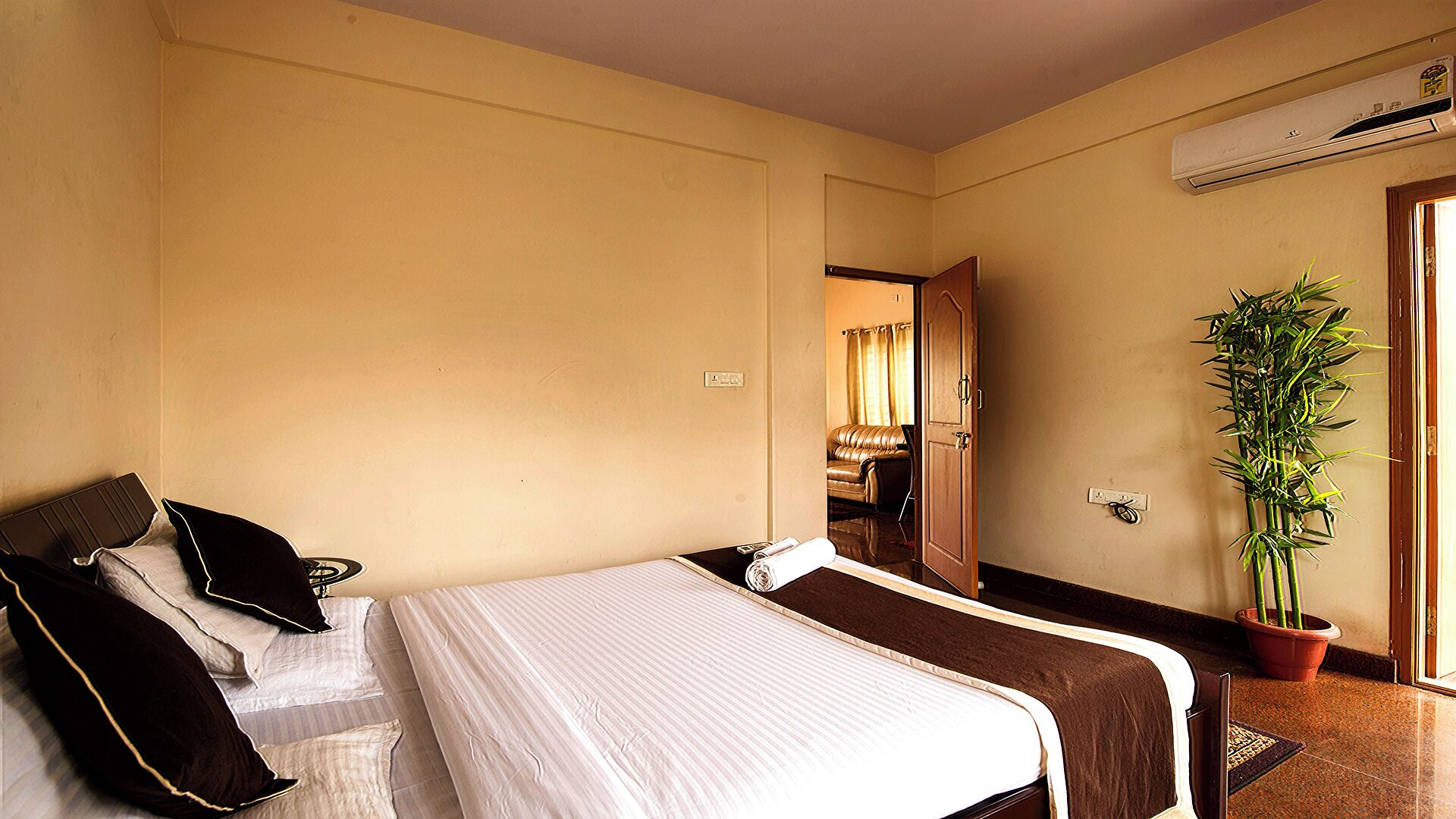 Habitación de hotel con dos camas, una planta en maceta y un equipo de aire acondicionado.