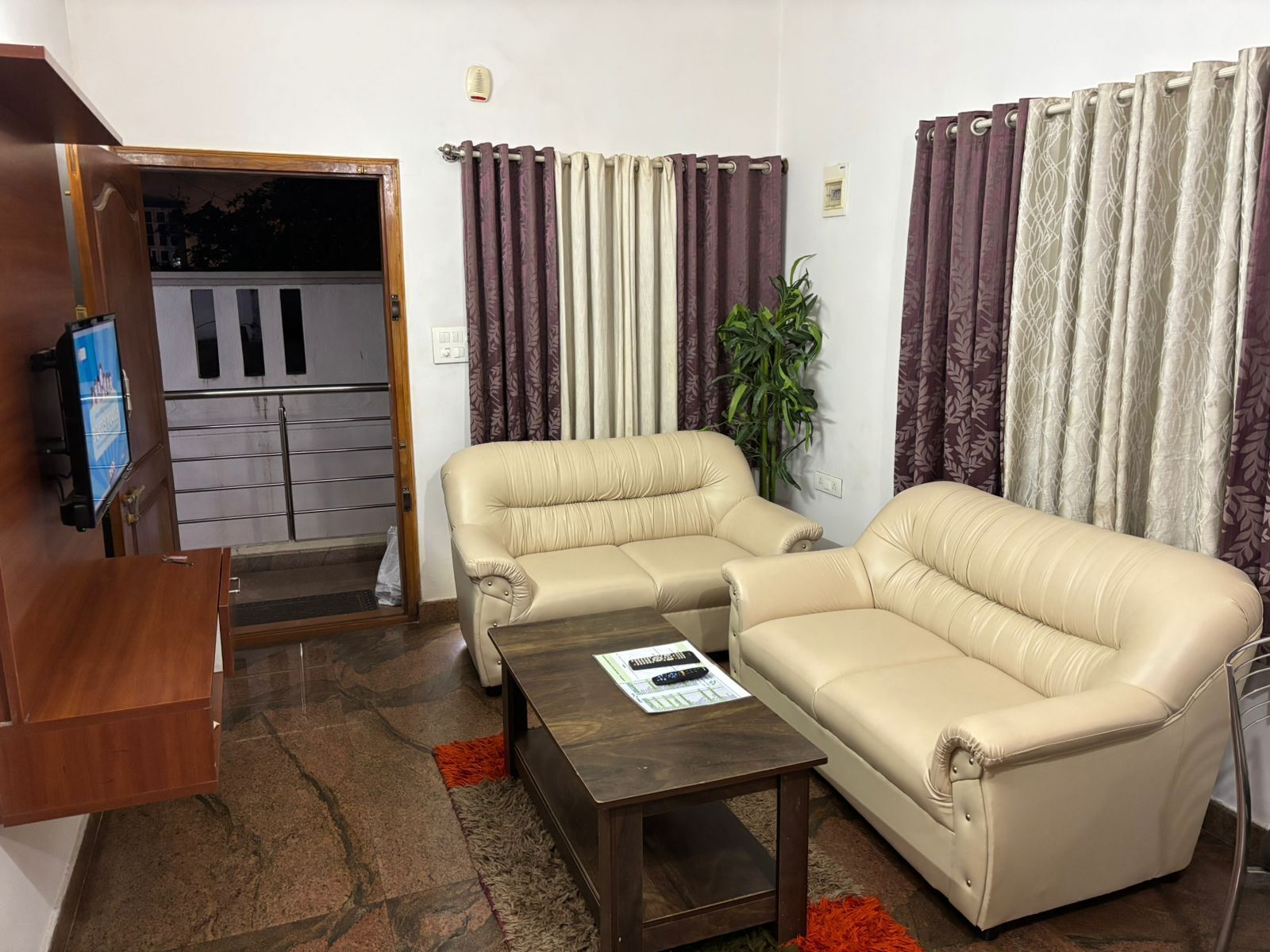Un salón con dos sofás beige, una mesa de centro y un televisor sobre un mueble de madera.