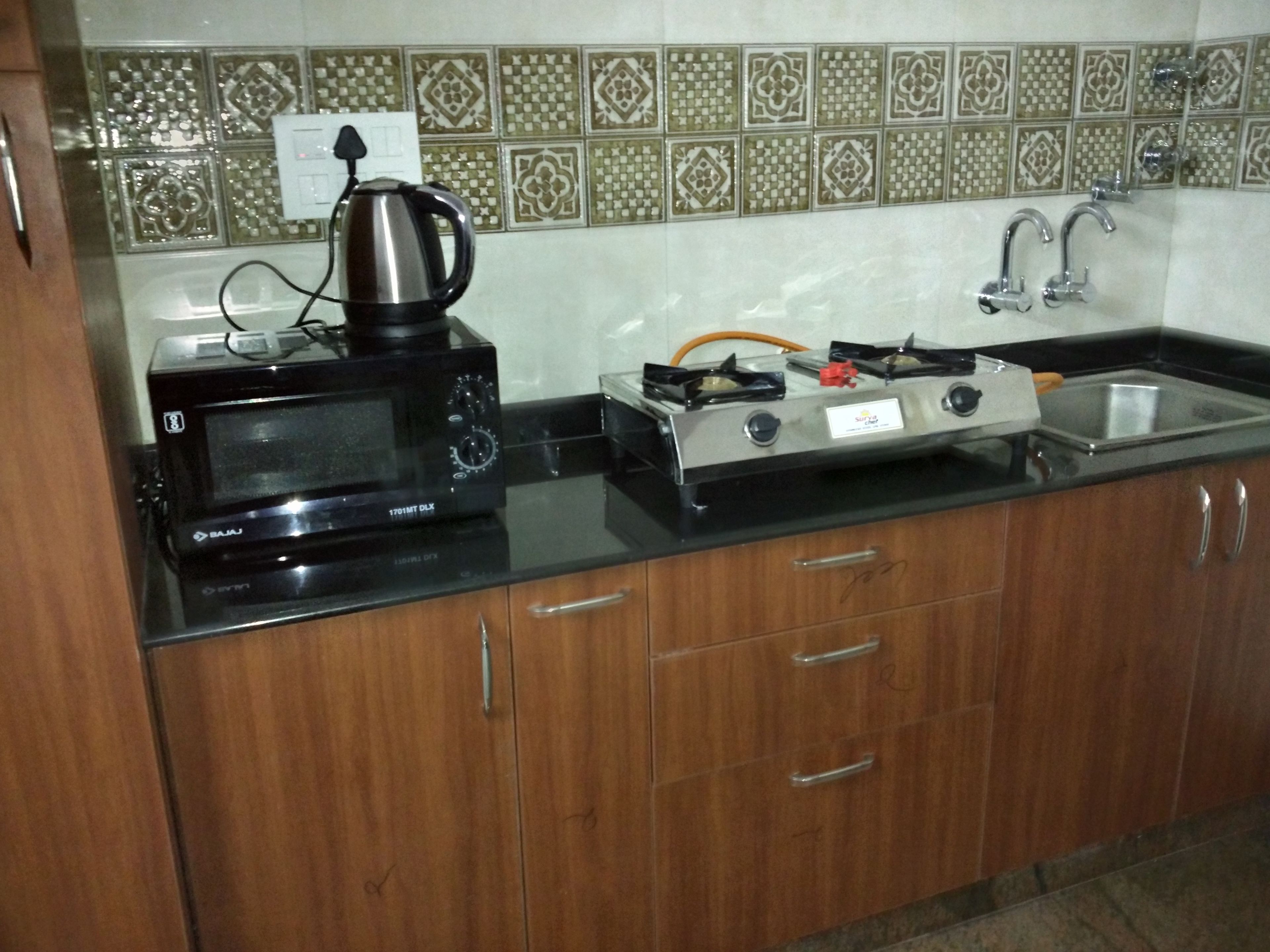 A kitchen with a microwave, toaster, kettle, and gas stove.