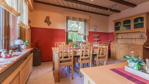 Un coin repas avec des meubles en bois, un mur d’accent rouge et une fenêtre agrémentée de rideaux.