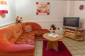 A living room with a sofa, a small table, a television, and a bookshelf.