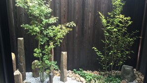 A garden with a wooden fence, rocks, and various plants. - Machiya Kamo River 7 (Kyoto)