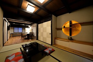 A traditional Japanese room with tatami flooring, a low table, and a sliding door. - Machiya Kamo River 7 (Kyoto)
