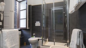 A modern bathroom with a glass-enclosed shower, a toilet, and a sink.