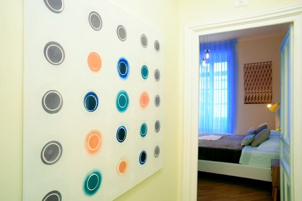 Una habitación con una cama, una pared con lámparas circulares y una ventana con cortinas azules.