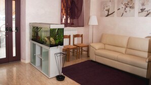 A living room with a fish tank, two chairs, a sofa, and a lamp. - Hotel Centrale (Loreto)