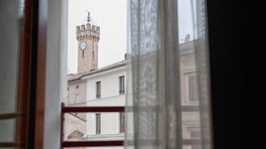 A view of a clock tower through a window with a curtain. - Hotel Centrale (Loreto)