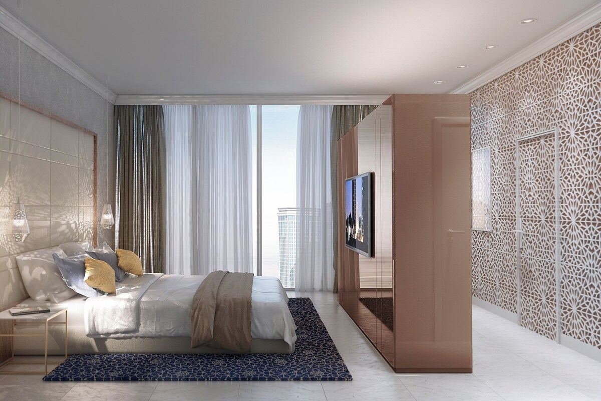 Moderni hotellihuone, jossa on sänky, televisio ja näkymä kaupunkiin.