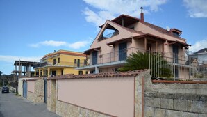Un edificio residencial con muro de piedra, balcón y cielo despejado.