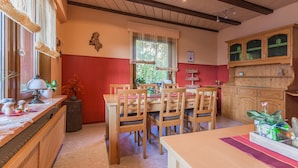Comedor con mobiliario de madera, una pared de acento roja y una ventana con cortinas.