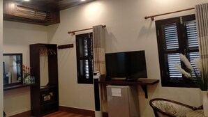 Una sala de estar con televisor, un refrigerador pequeño, un mueble de madera y una silla.