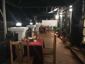 An outdoor patio area with tables and chairs, potted plants, and a railing. - Sakaodeuan Hotel (Luang Prabang)
